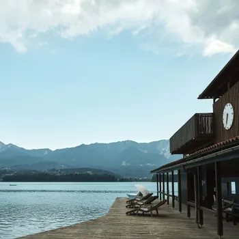 Private lakeside beach Lakefront wooden building with clock, deck chairs, and mountain view in the background